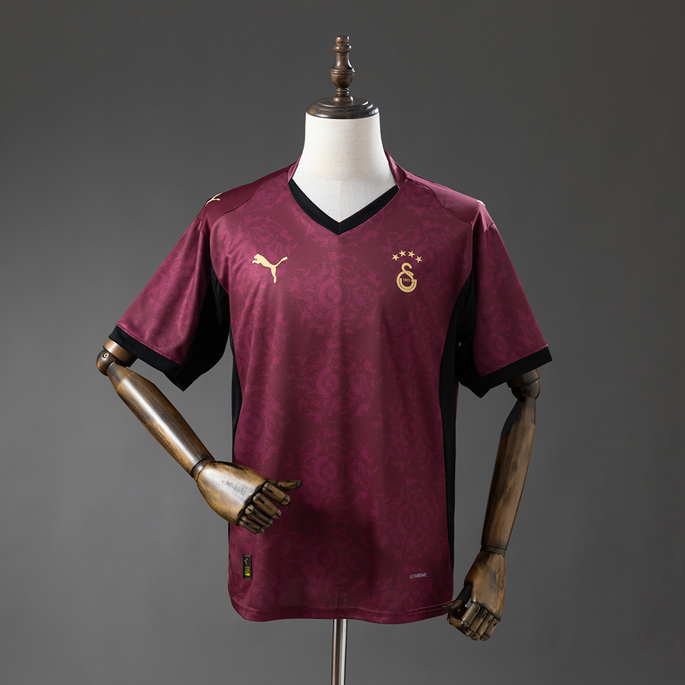 Mens Galatasaray Third Jersey 2025/26 Mens Galatasaray Third Jersey 2025/26 on rack showing deep maroon damask body with black V-neck insert and gold crest