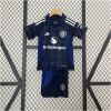 Kids Manchester United Away Kit 2024/25 on hanger showing navy monogram shirt with royal blue polo collar and shorts