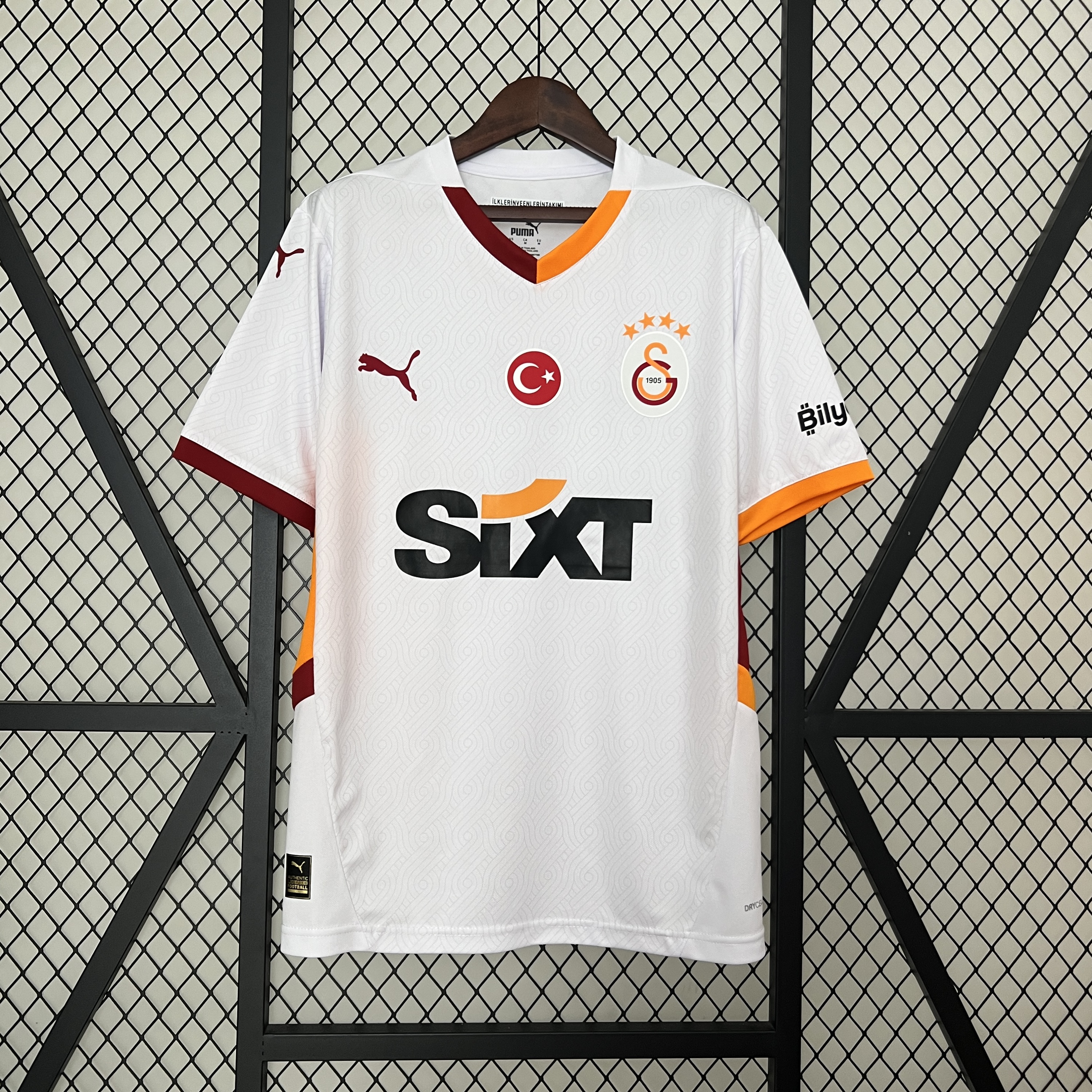 Mens Galata Away Jersey 2024/25 Mens Galata Away Jersey 2024/25 on display showing off-white body with wavy watermark graphics and split orange-maroon collar