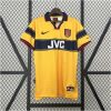 Mens Arsenal Retro Away Jersey 1997/99 on hanger showing yellow body with navy chest stripe, red piping, and JVC sponsor