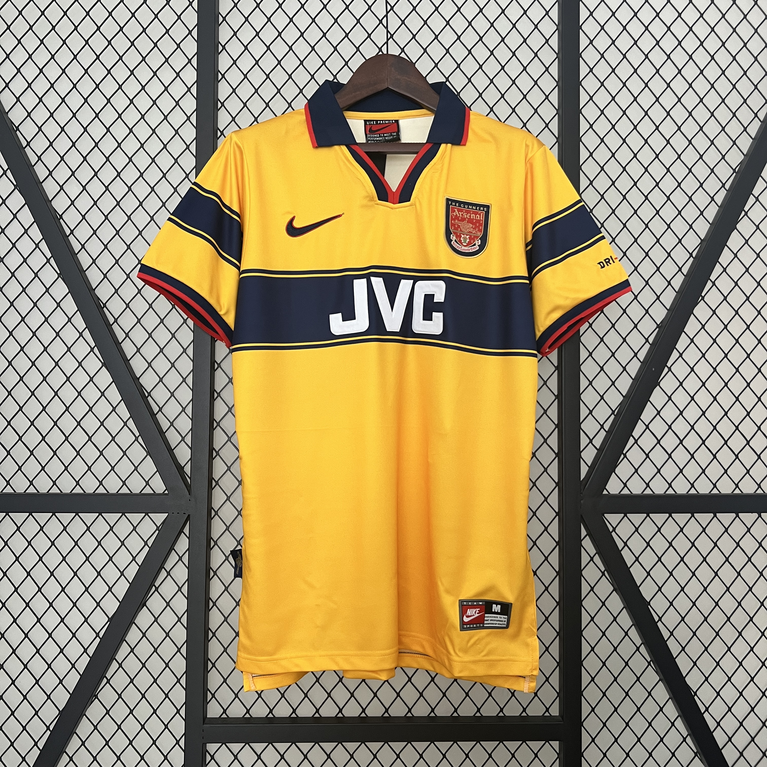 Mens Arsenal Retro Away Jersey 1997/99 Mens Arsenal Retro Away Jersey 1997/99 on hanger showing yellow body with navy chest stripe, red piping, and JVC sponsor