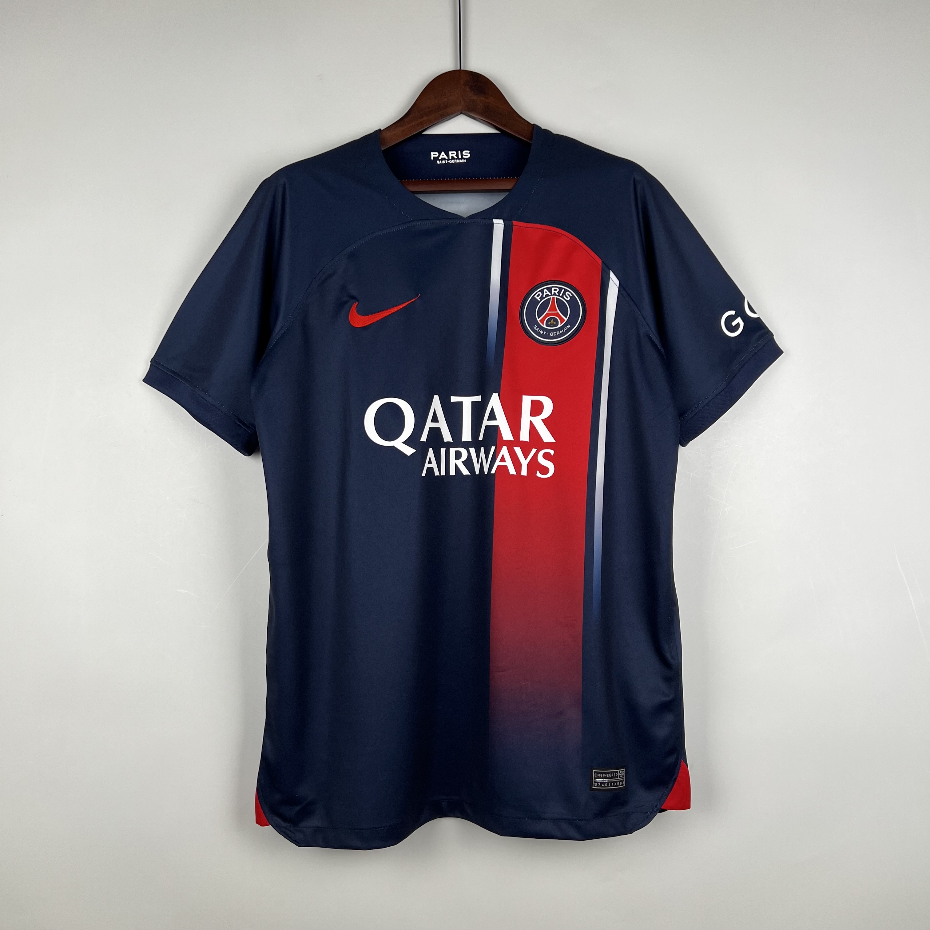Mens PSG Home Jersey 2023/24 Mens PSG Home Jersey 2023/24 on hanger displaying midnight navy body with red-to-blue gradient vertical stripe