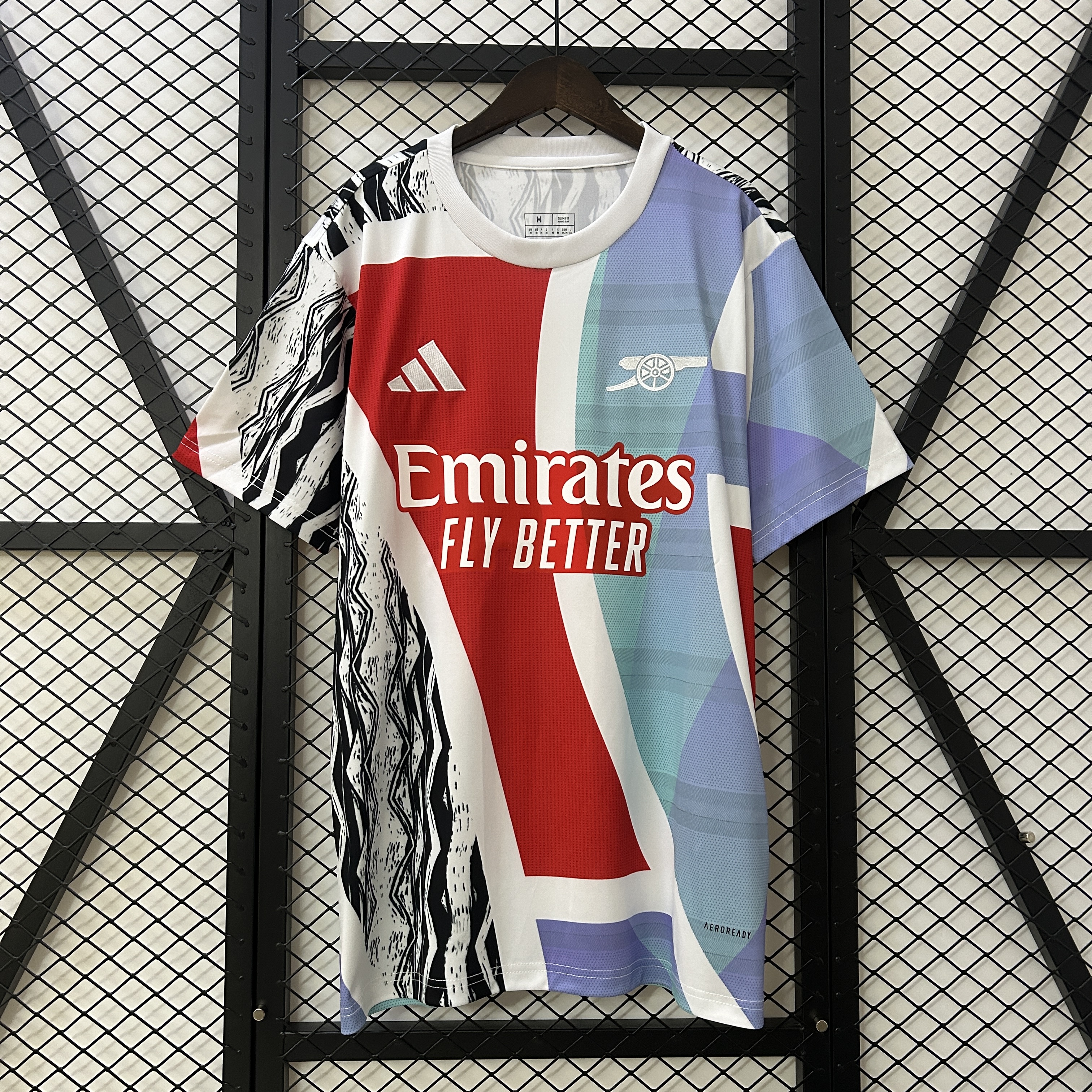 Mens Arsenal adidas Pre-Match Jersey 2024/25 Mens Arsenal adidas Pre-Match Jersey 2024/25 on hanger showing split graphic body with red, lavender, and geometric panels