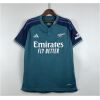 Mens Arsenal Third Jersey 2023/24 on hanger showing mineral teal body with navy raglan sleeves and cannon badge