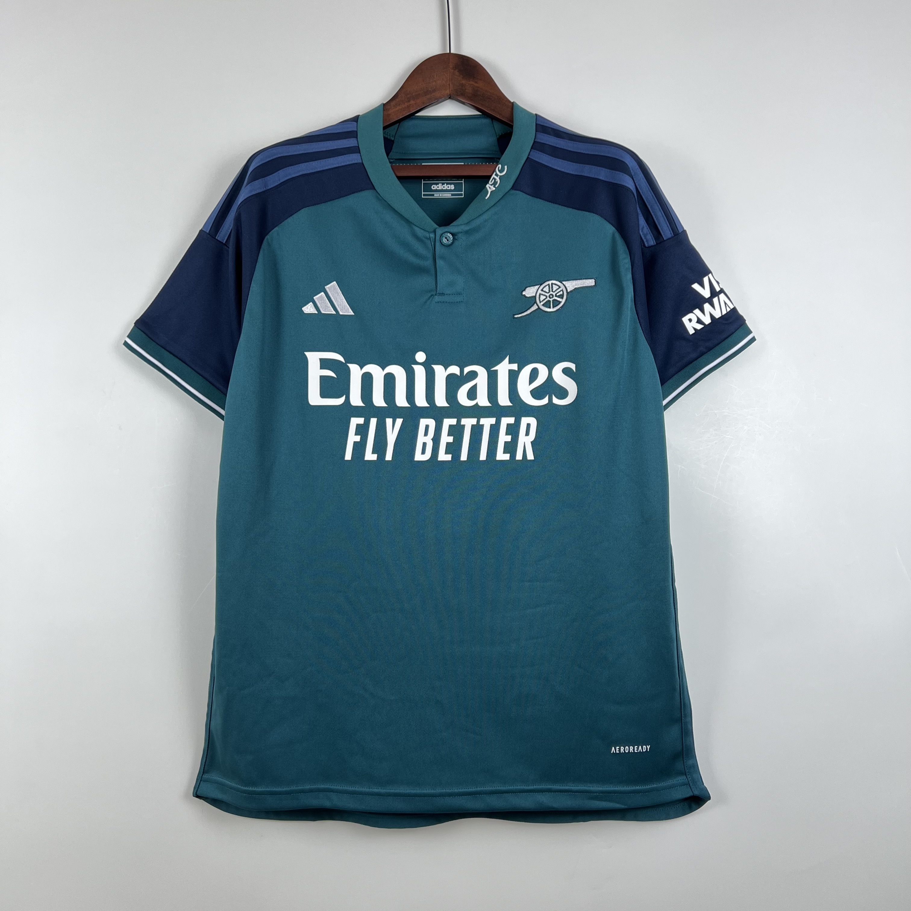 Mens Arsenal Third Jersey 2023/24 Mens Arsenal Third Jersey 2023/24 on hanger showing mineral teal body with navy raglan sleeves and cannon badge