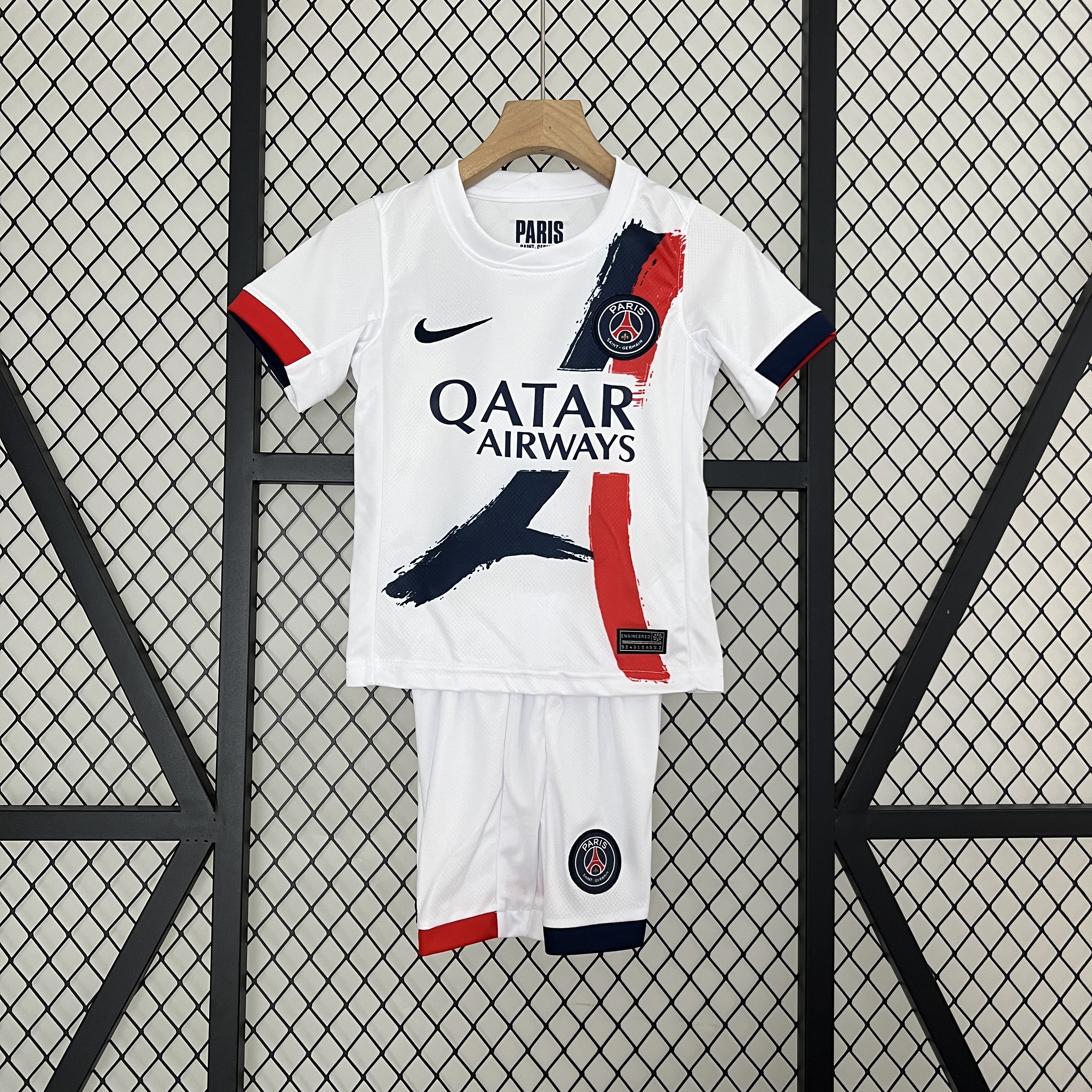Kids PSG Away Kit 2024/25 Kids PSG Away Kit 2024/25 featuring white youth away jersey with Eiffel Tower graphic and matching shorts