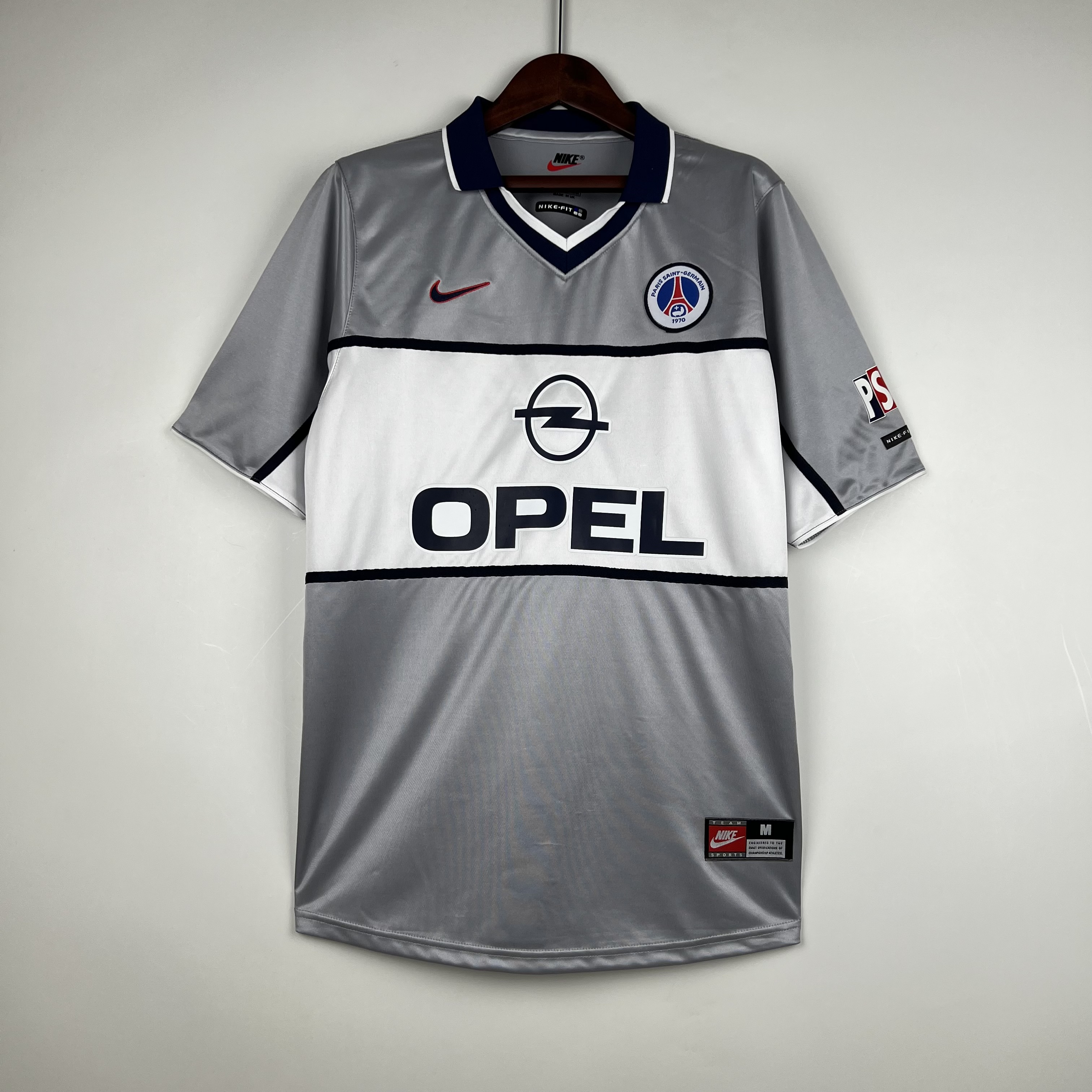 Mens PSG Retro Away Jersey 1999/00 Mens PSG Retro Away Jersey 1999/00 on hanger displaying silver-grey body and white chest band with OPEL logo
