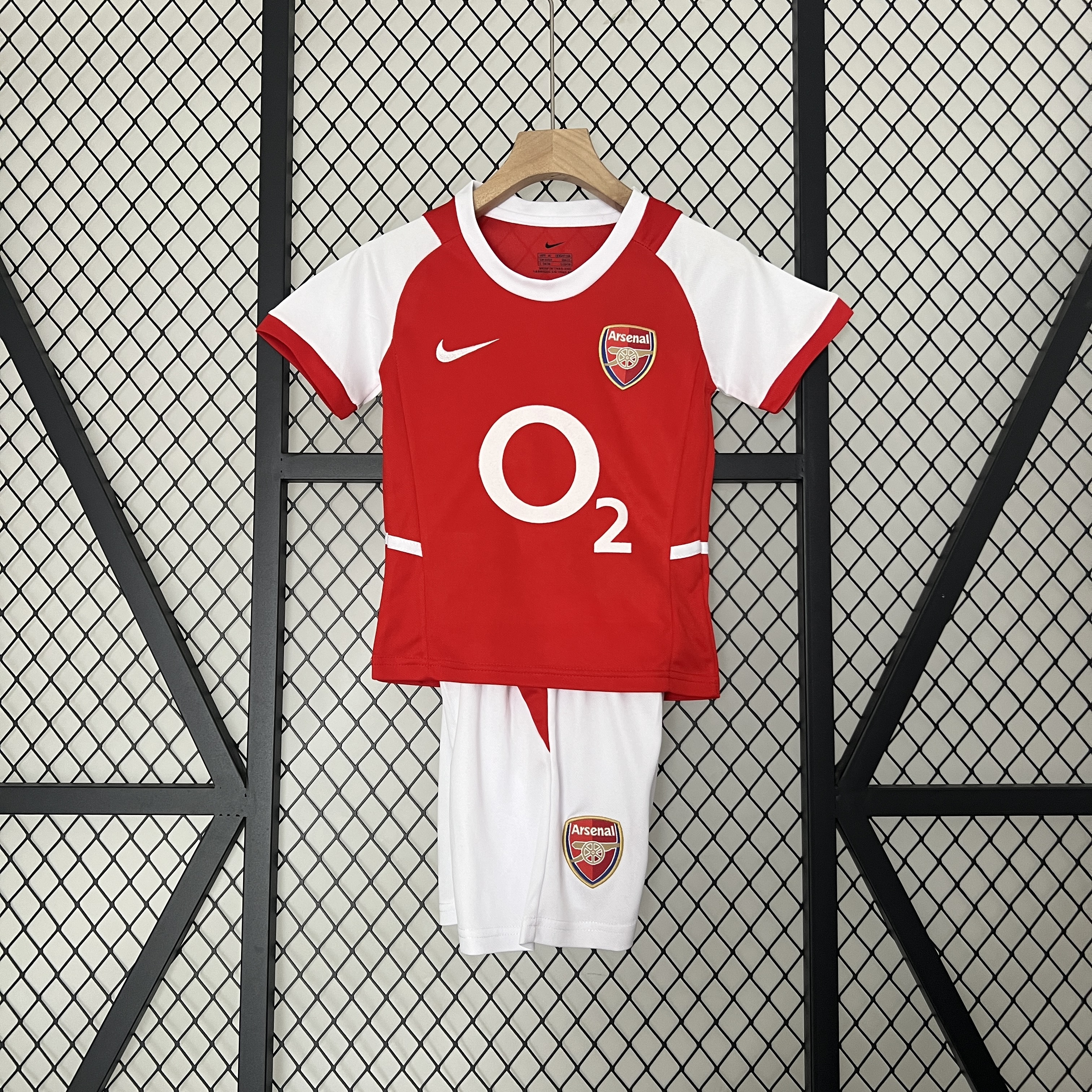Kids Arsenal Retro Home Kit 2002/04 Kids Arsenal Retro Home Kit 2002/04 on rack showing red and white jersey with matching white shorts and O2 logo