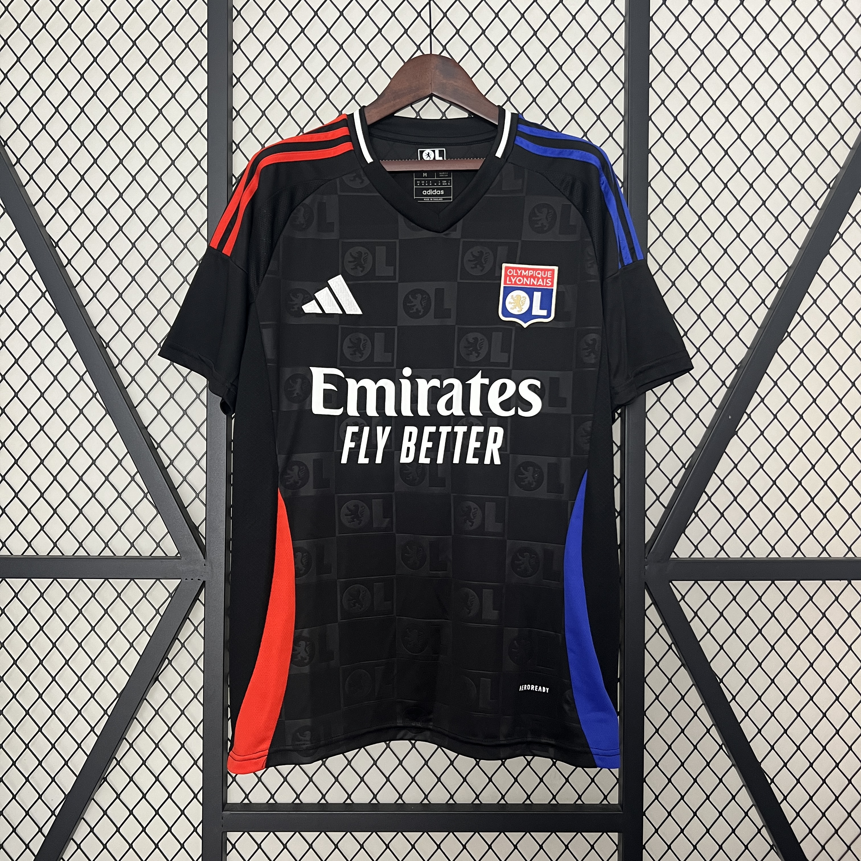 Mens Lyon Away Jersey 2024/25 Mens Lyon Away Jersey 2024/25 on hanger showing matte black body and asymmetric red-blue shoulder stripes