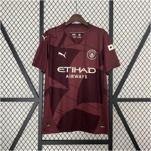 Mens Manchester City Third Jersey 2024/25 on hanger showing maroon body with tonal geometric panels and gold sponsor