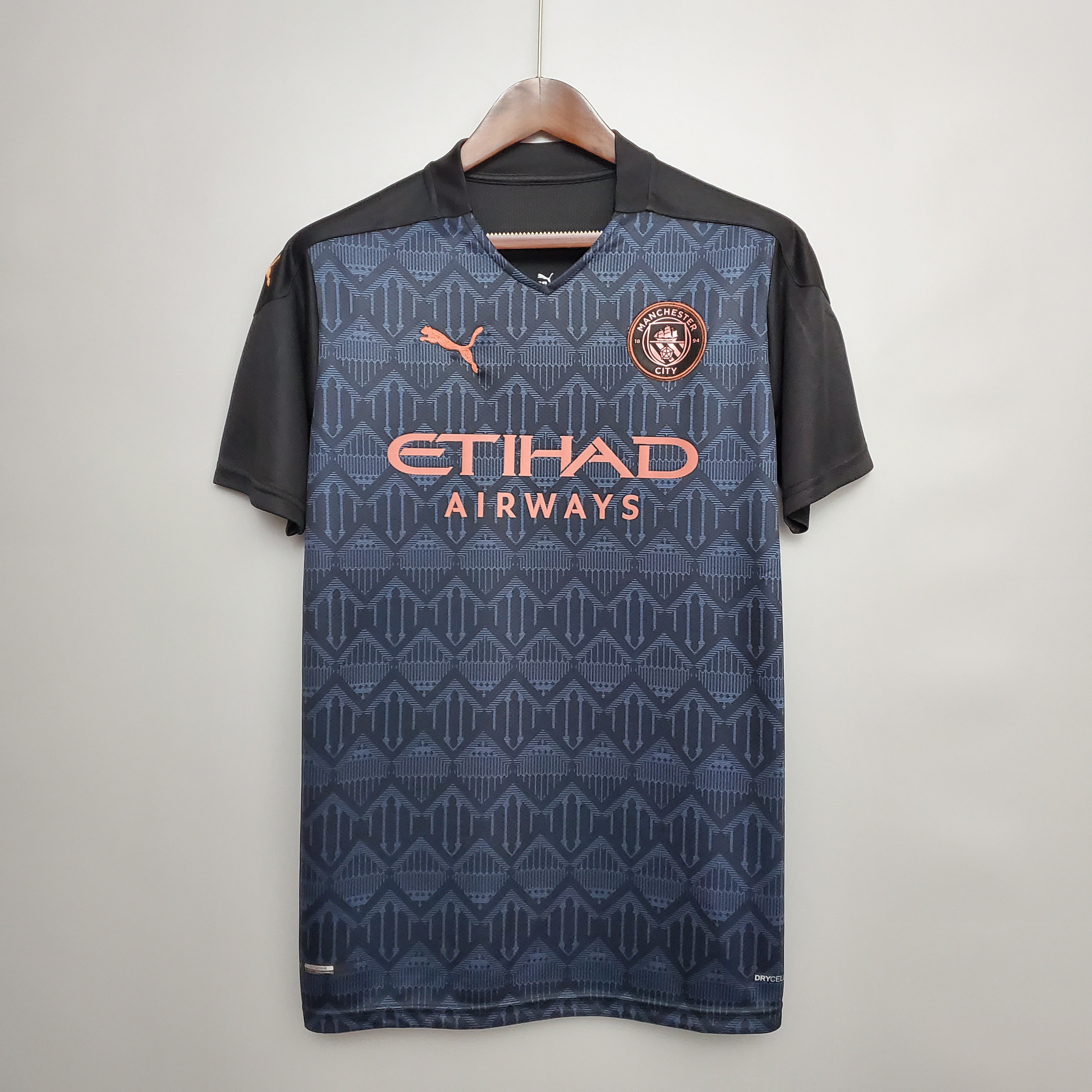 Mens Manchester City Retro Away Jersey 2020/21 Mens Manchester City Retro Away Jersey 2020/21 on hanger showing dark navy Castlefield mosaic pattern with rose gold crest