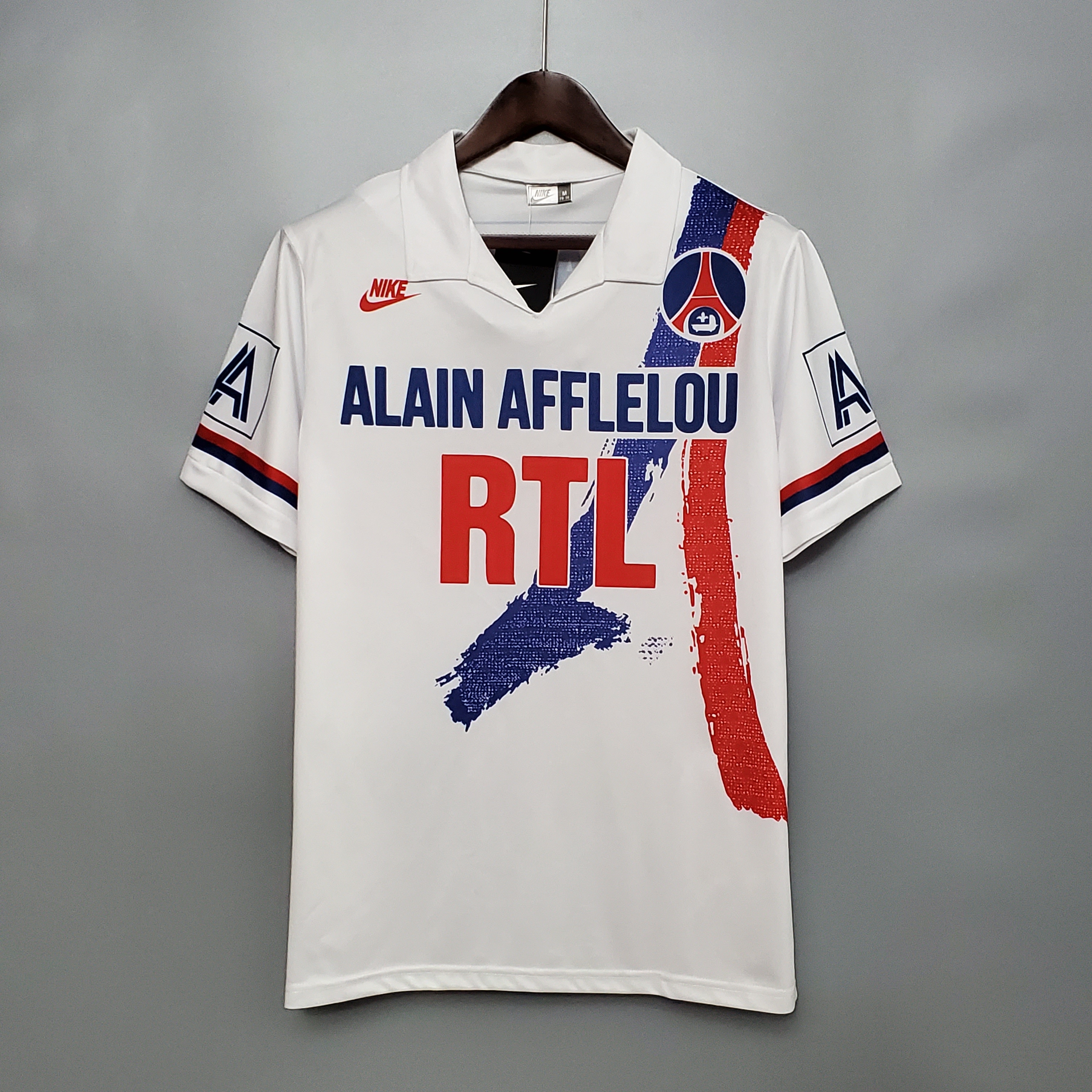 Mens PSG Retro Home Jersey 1990/92 Mens PSG Retro Home Jersey 1990/92 on hanger showing white shirt with painterly Eiffel Tower brushstroke and RTL sponsor