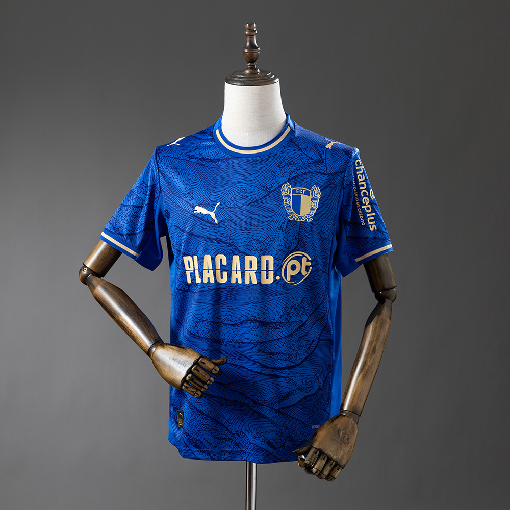 Mens Famalicao Away Jersey 2025/26 Mens Famalicao Away Jersey 2025/26 on mannequin showing royal blue topographic body with gold trims and PLACARD.pt logo