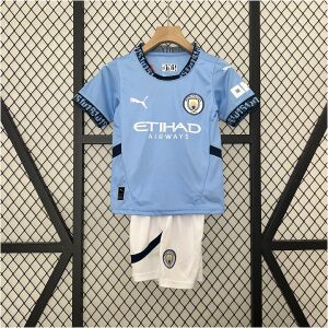 Kids Manchester City Home Kit 2024/25 display showing sky blue shirt with 0161 collar and matching white athletic shorts