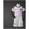 Front view of the Kids Chile Away Kit 2026 showing the white jersey with pink floral graphics and matching white shorts on a mannequin.