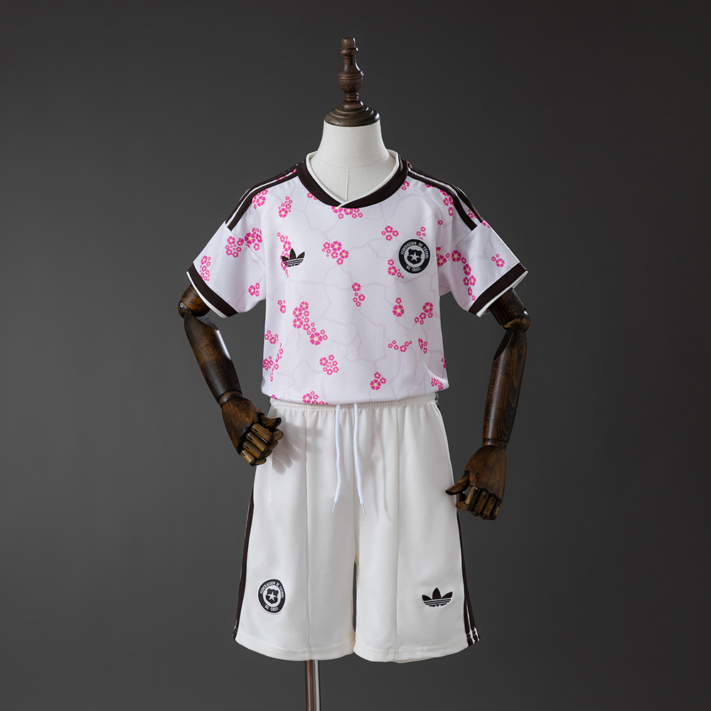 Kids Chile Away Kit 2026 Front view of the Kids Chile Away Kit 2026 showing the white jersey with pink floral graphics and matching white shorts on a mannequin.