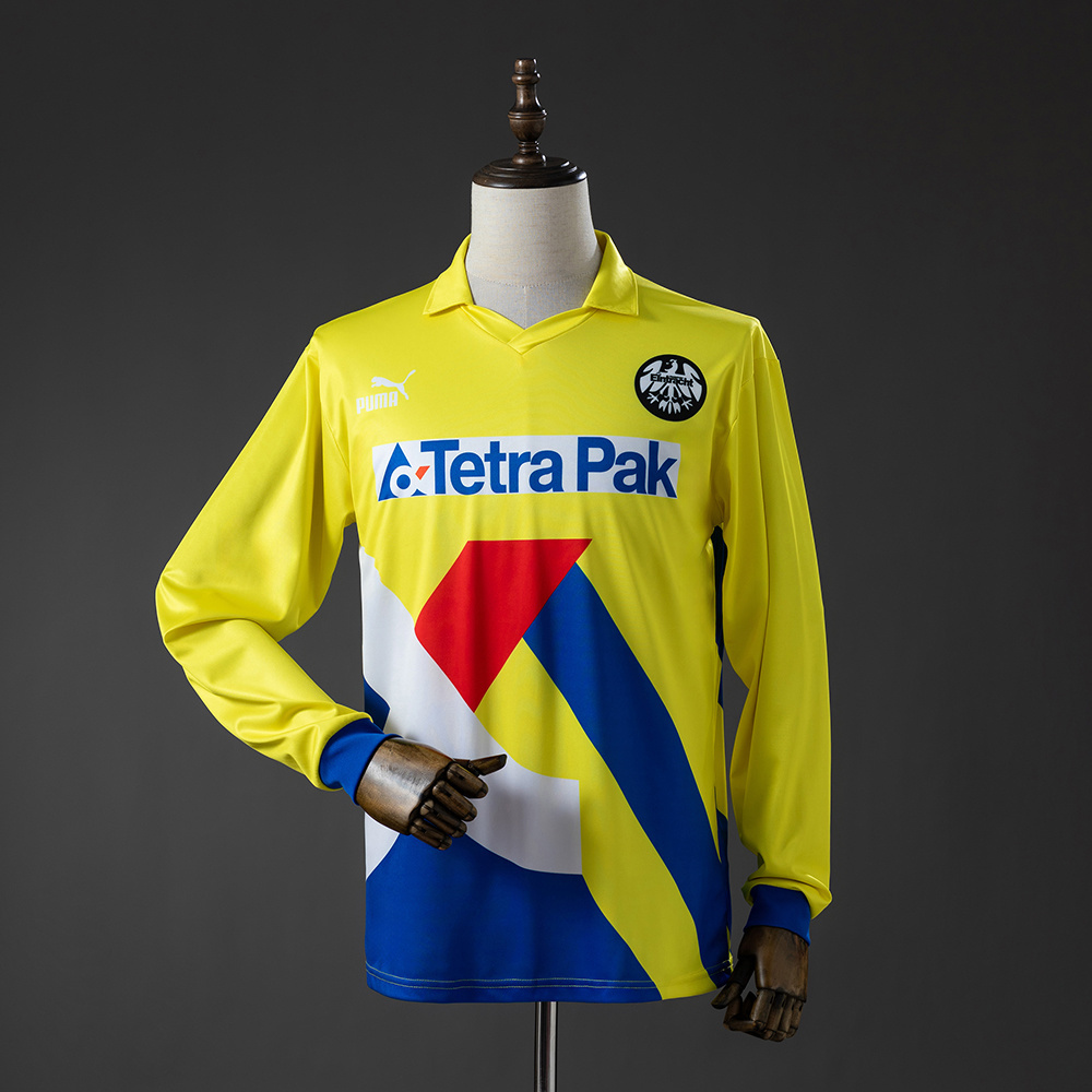 Mens Frankfurt Retro Long Sleeve Away Jersey 1993/96 Front view of the Mens Frankfurt Retro Long Sleeve Away Jersey 1993/96 in yellow with blue and red geometric shapes