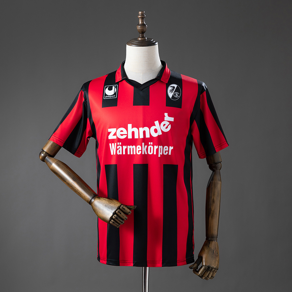 Mens SC Freiburg Retro Home Jersey 1994/95 Front view of the Mens SC Freiburg Retro Home Jersey 1994/95 in red and black vertical stripes with Zehnder sponsor