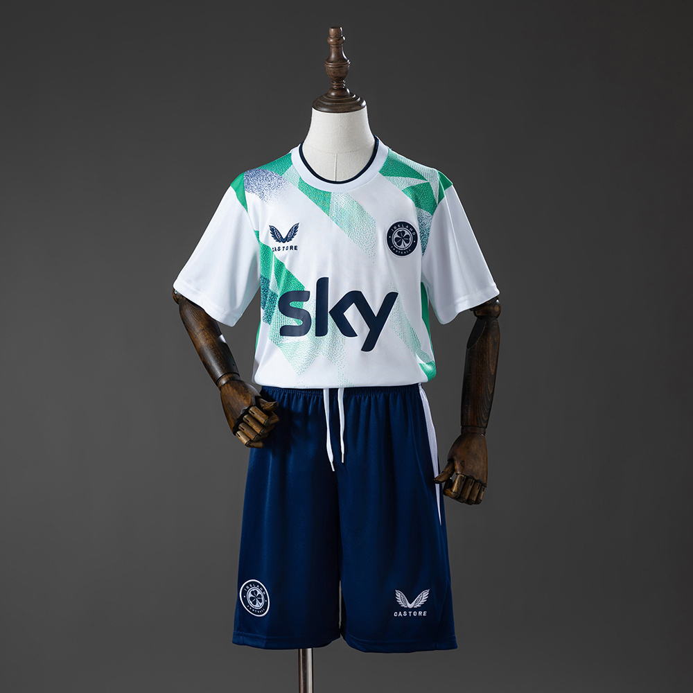 Kids Ireland Away Kit 2026 Front view of the Kids Ireland Away Kit 2026 featuring white geometric pattern jersey, Sky sponsor, and navy shorts