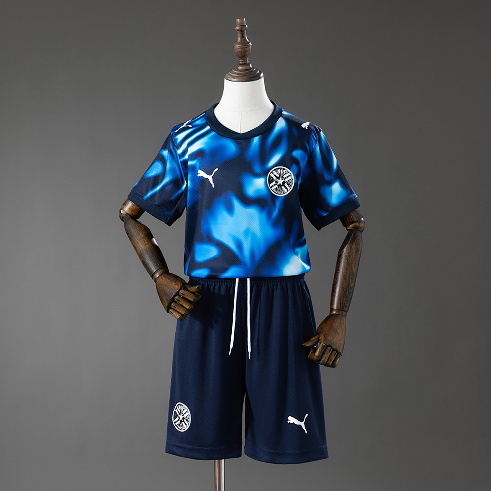 Kids Paraguay Away Kit 2026 Kids Paraguay Away Kit 2026 front view showing blue and cyan smoke graphic jersey with navy shorts