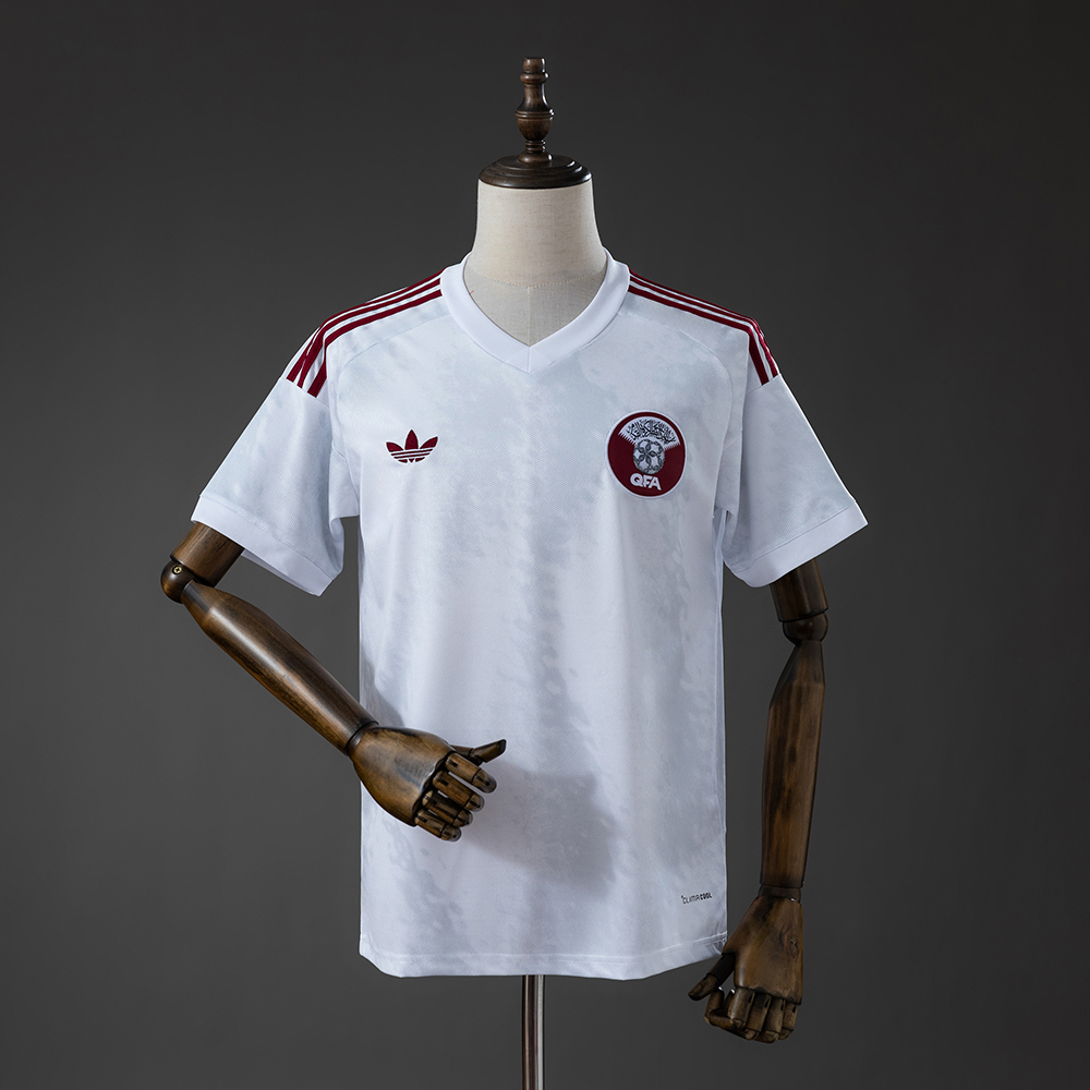Mens Qatar Away Jersey 2026 Mens Qatar Away Jersey 2026 front view in white with maroon shoulder stripes and circular QFA crest