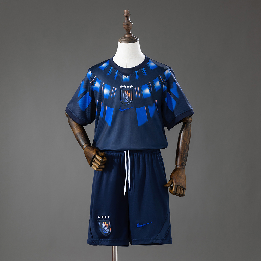 Kids Uruguay Away Kit 2026 Kids Uruguay Away Kit 2026 front view of navy jersey and shorts with sunbeam graphic and AUF crest