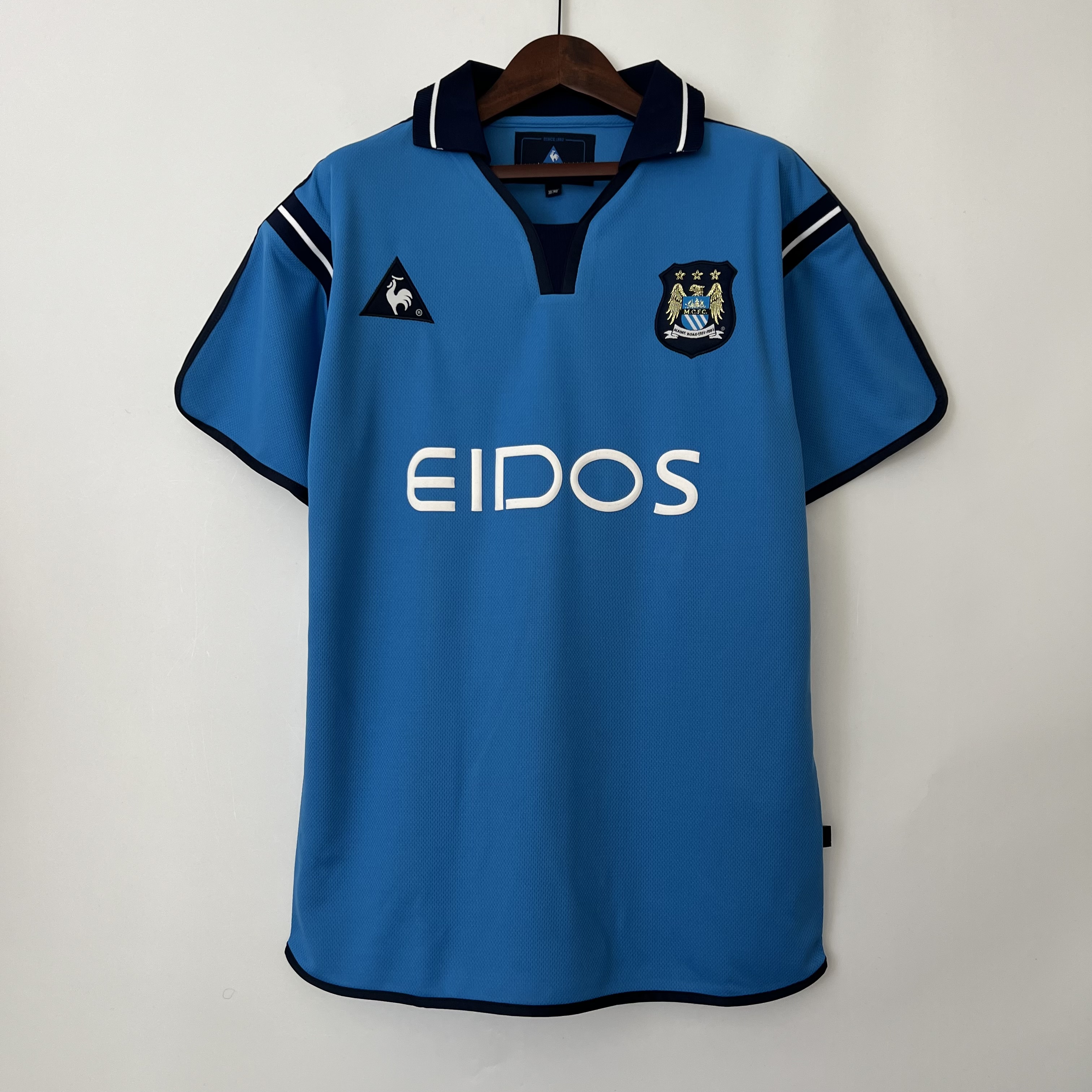 Mens Manchester City Retro Home Jersey 2001/02 Mens Manchester City Retro Home Jersey 2001/02 on hanger showing sky blue body with navy collar and white EIDOS sponsor