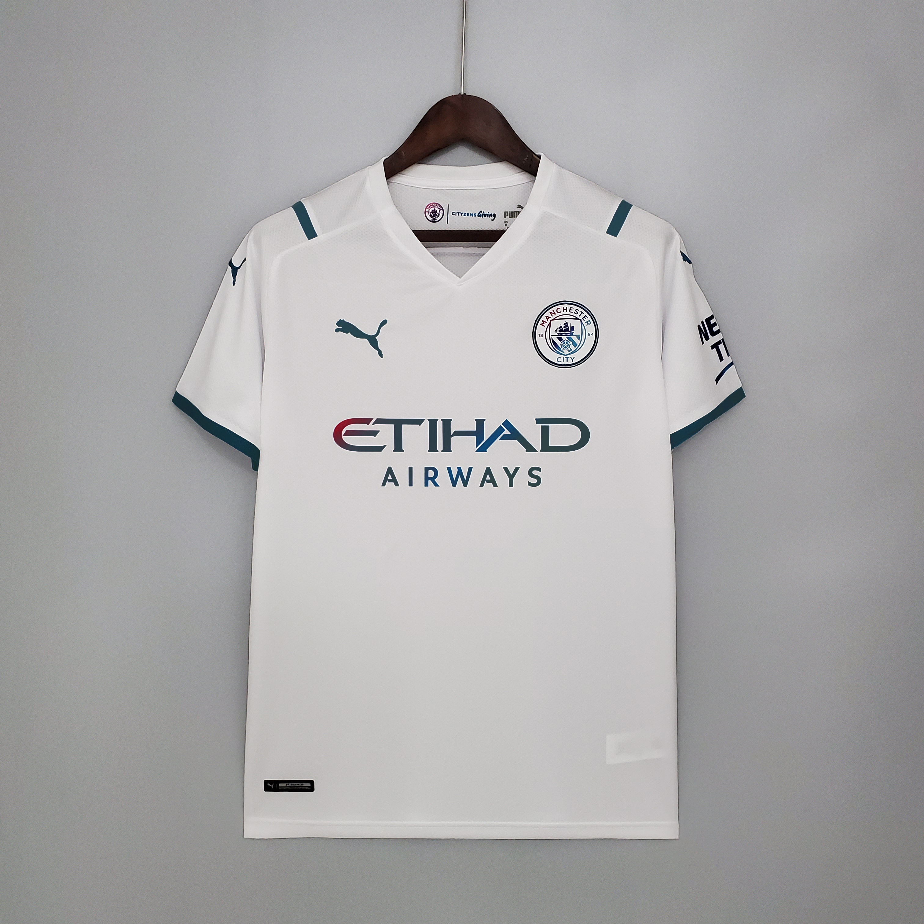 Mens Manchester City Away Jersey 2021/22 Mens Manchester City Away Jersey 2021/22 on hanger showing white body with teal shoulder accents and iridescent sponsor