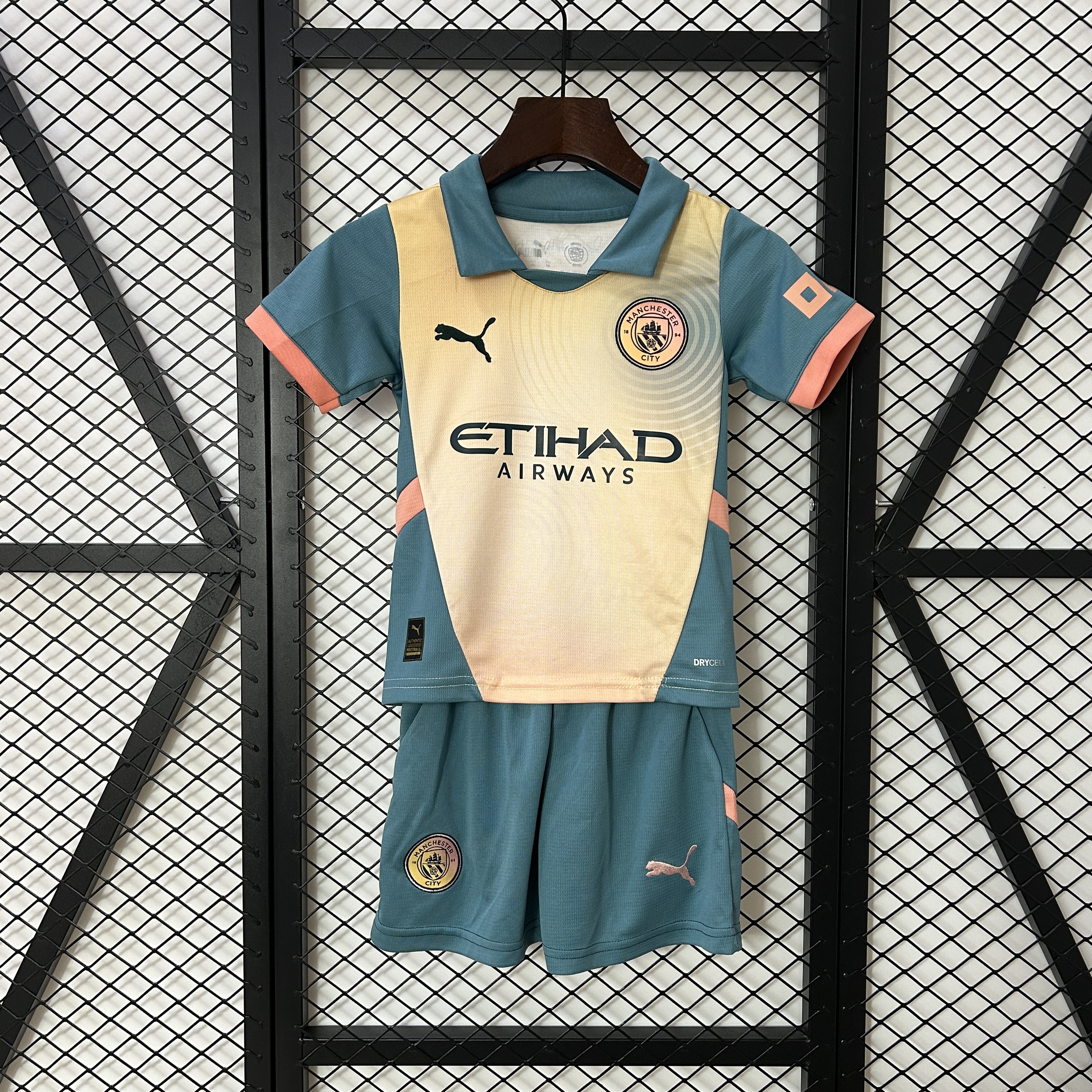 Kids Manchester City Fourth Kit 2024/25 Kids Manchester City Fourth Kit 2024/25 display showing slate teal and pale yellow shirt with matching athletic shorts