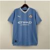 Mens Manchester City Home Jersey 2023/24 on hanger showing sky blue body with embossed vertical stripes and white sponsor