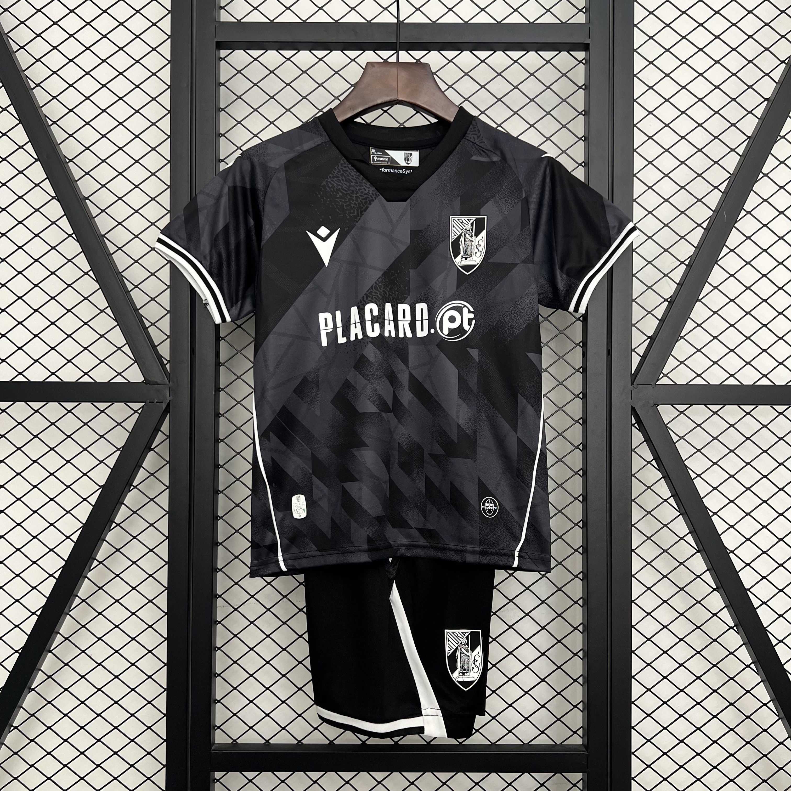 Kids Vitoria SC Away Kit 2025/26 Kids Vitoria SC Away Kit 2025/26 on rack showing charcoal black geometric jersey with white trims and matching shorts
